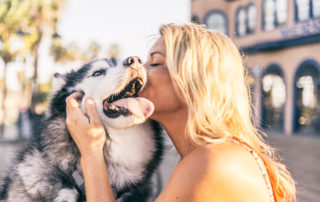 young professional woman snuggling with her husky pet